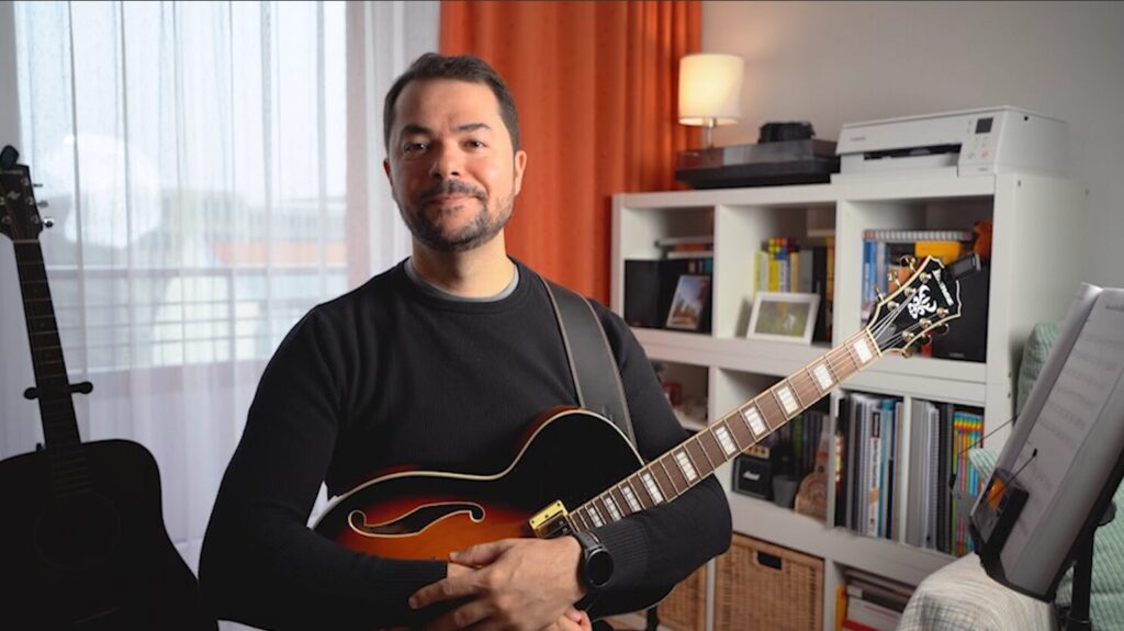 Julio's image holding his guitar on his practice space